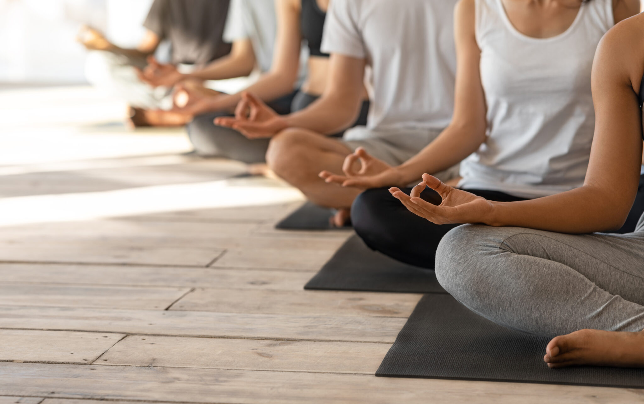 Unrecognizable Group Of People Practicing Yoga Together In Studio, Meditating In Lotus Position And Showing Mudra Gestures, Sitting Relaxed On Mats In A Row, Cropped Image With Free Space